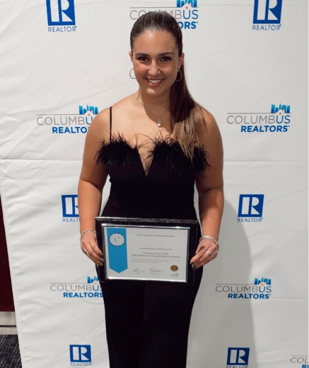 A woman in a black dress holding a plaque.